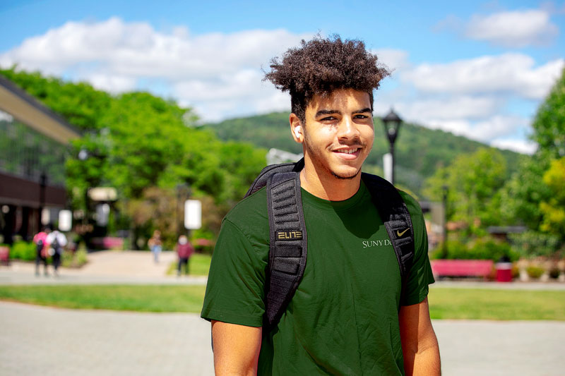 Student smiling with green mountains in the background