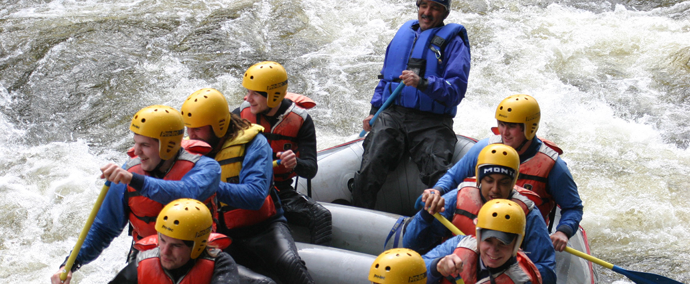 Students whitewater rafting in a rapid on the river