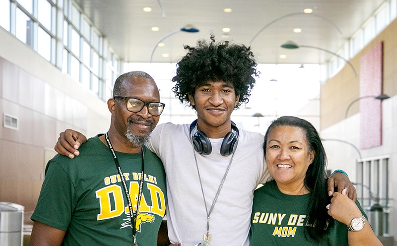 A student smiles with parents
