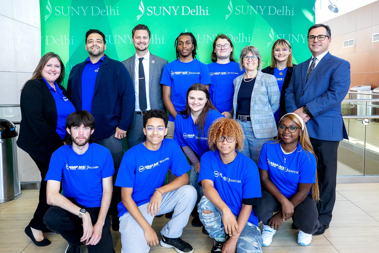 Group of studdents posing in front of a green backdrop