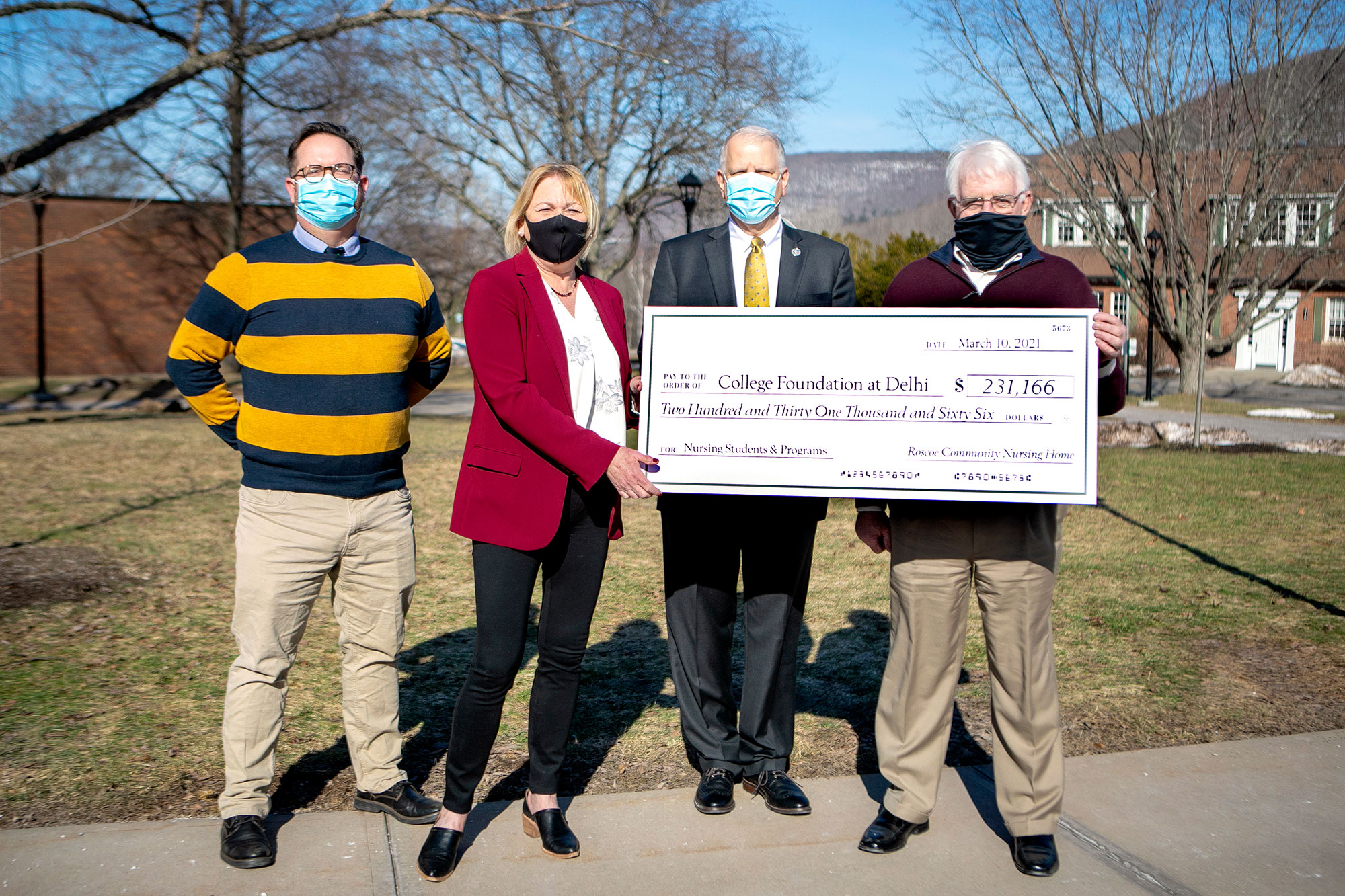 4 people standing with giant check