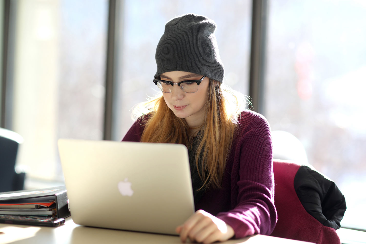 Student with beaniie looking at laptop