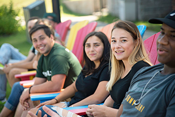 Students relaxing on adirondack chairs on campus