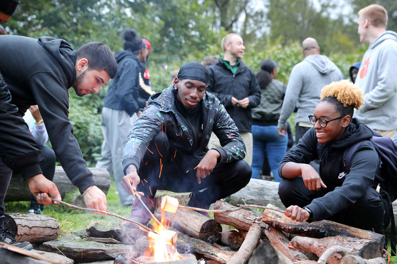 Student toasting marshmallows over a campfire