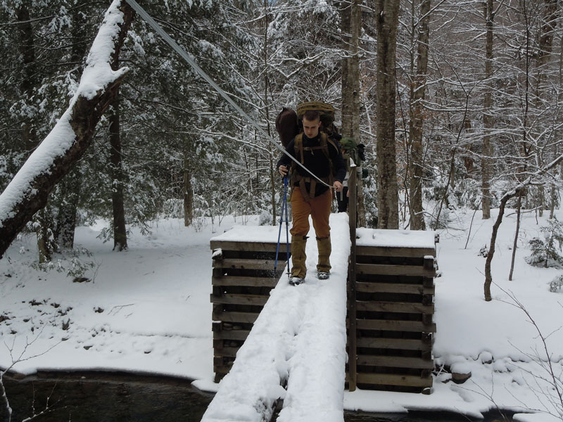 Student holding poles going down incline outside in snow