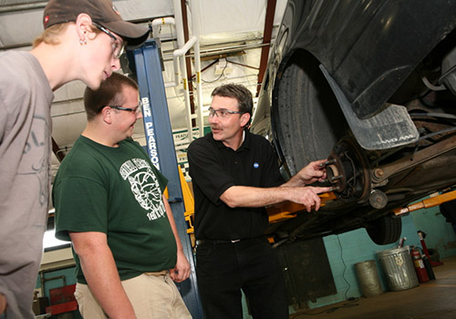 Students working on a car with an instructor