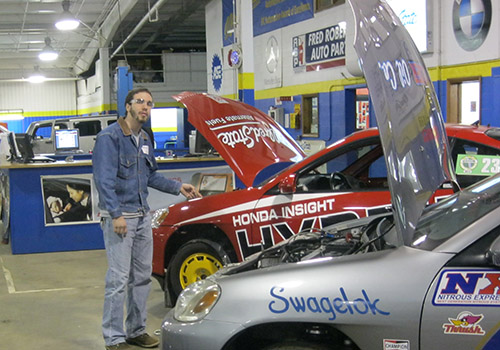 Student checking under the hood of a car