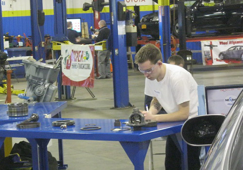 Student working on automotive parts laid out on a table