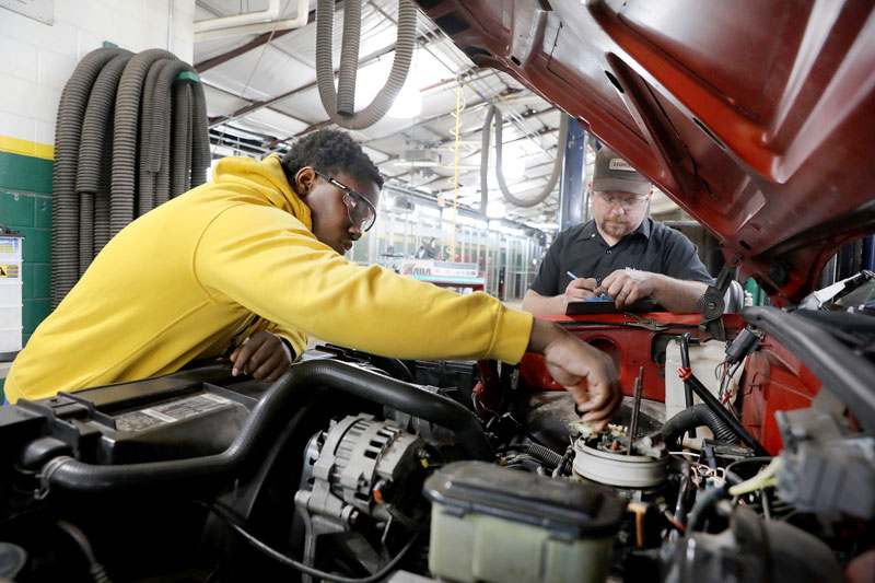 Student and faculty working under the hood in automotive lab