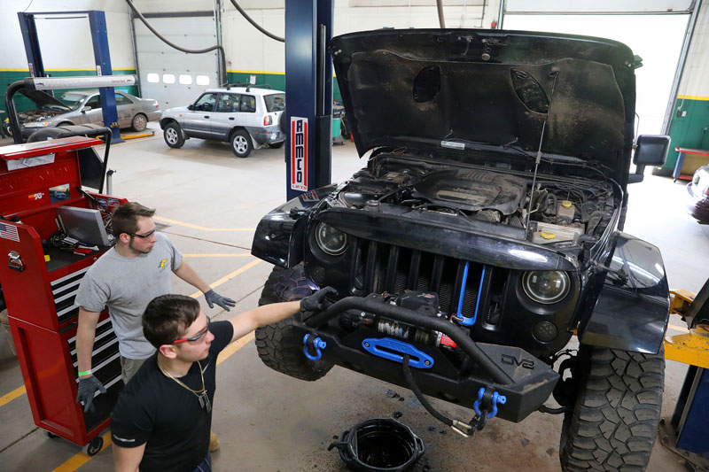 Automotive students looking at car on the lift in automotive lab