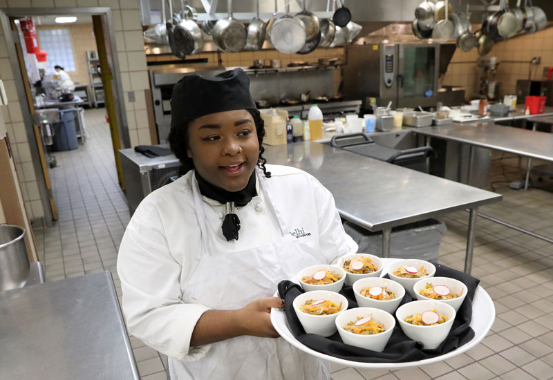 Culinary student carrying a tray of food