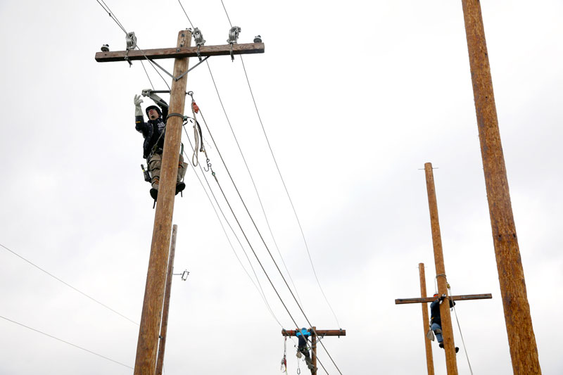 Student working at top of utility pole