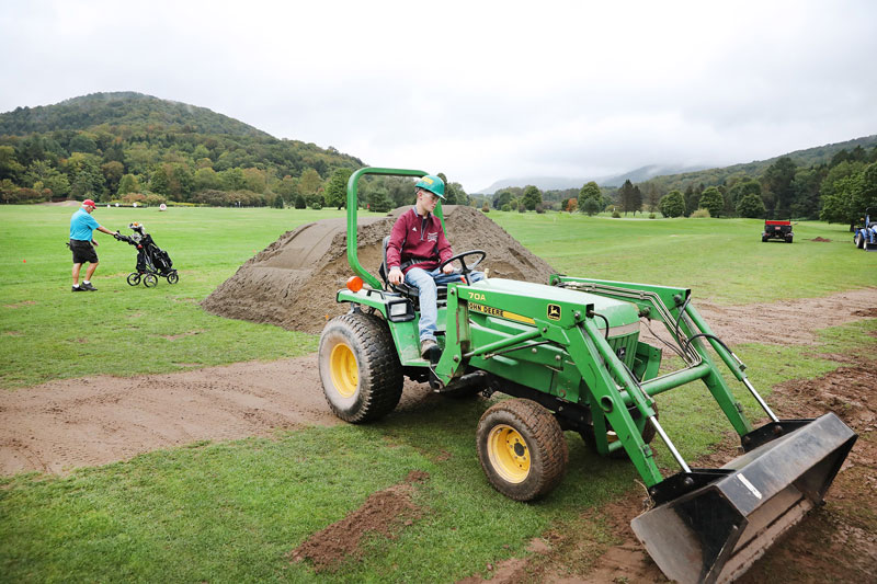 Student operating John Deere lawn equipment on golf course