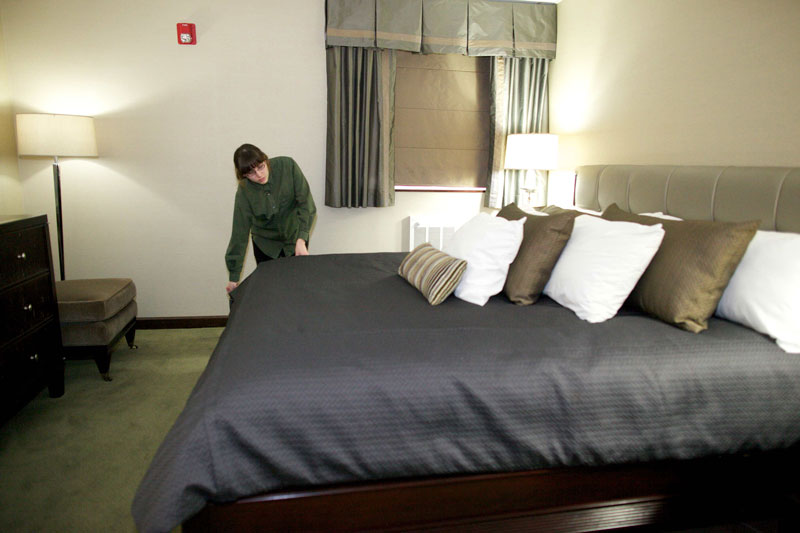 Student making a bed in hotel room on campus