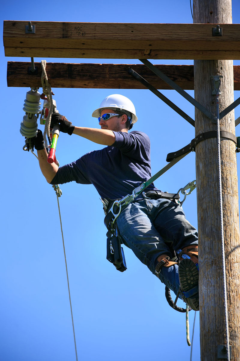 Student working at top of utility pole