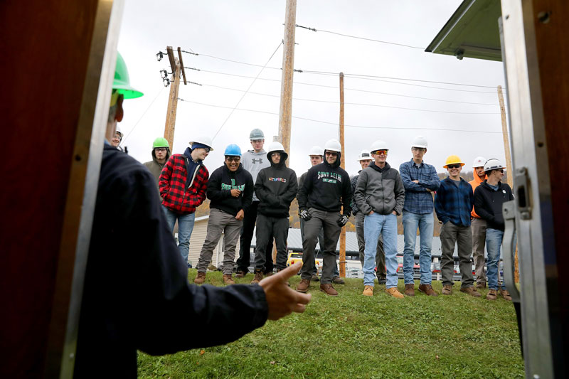 Students in hard hats listening to faculty member