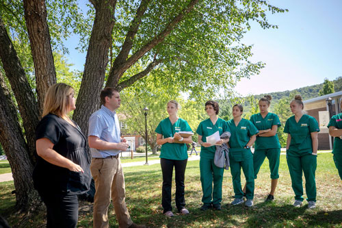 Students listening to faculty outdoors