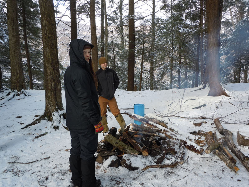 Students building a fire in snow covered woods