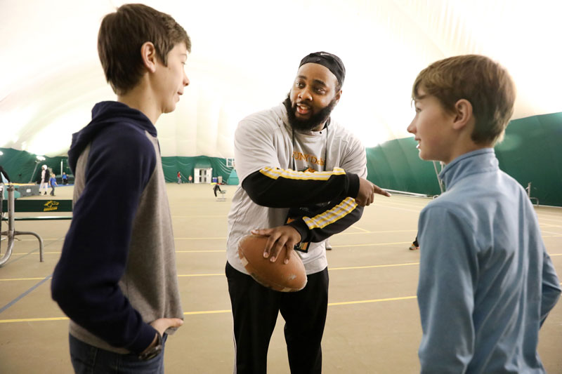 Student holding football working with young people