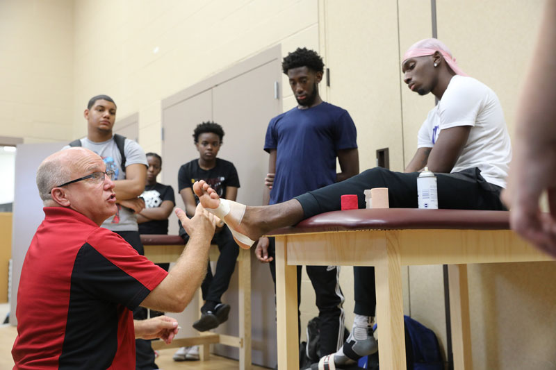 Faculty member wrapping student's foot 