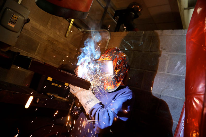 Student welding in welding gear