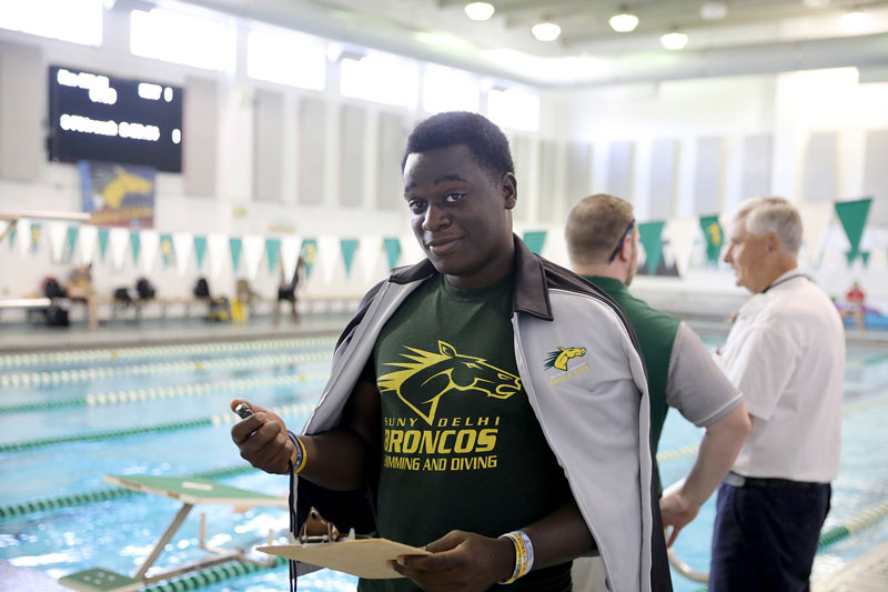 Student in Bronco shirt standing beside swimming pool