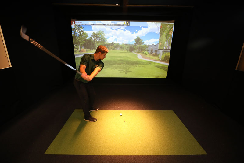 Student practicing golf swing in indoor swing analysis lab