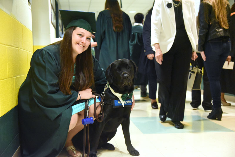 Graduate in cap and gown with Guiding Eyes dog