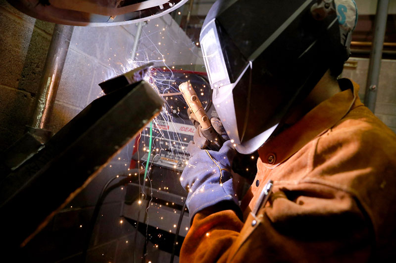 Student welding in lab in protective gear