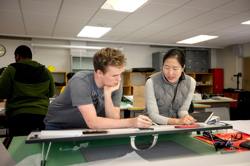 Architecture student and faculty member discussing drawing