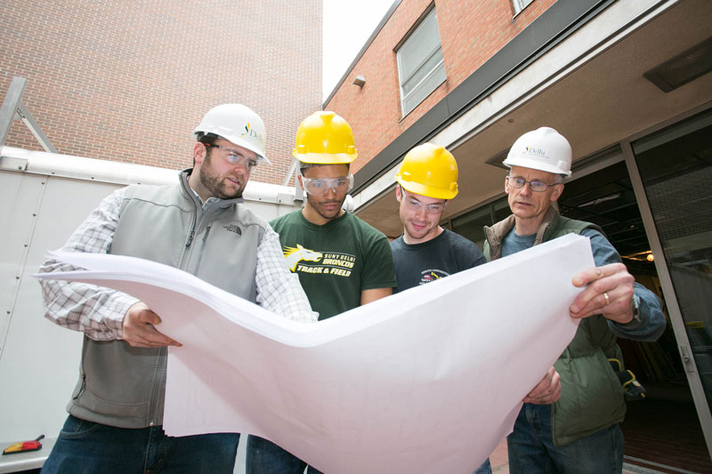 Students and faculty looking at blueprints