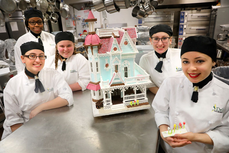 Students displaying gingerbread house they created