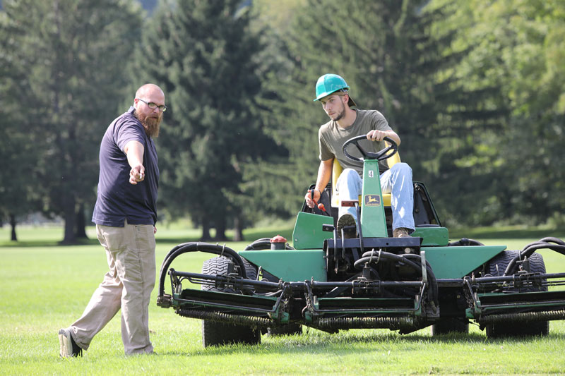Student driving turf equipment on golf course
