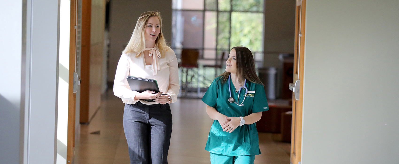 Two students walking down hallway in conversation