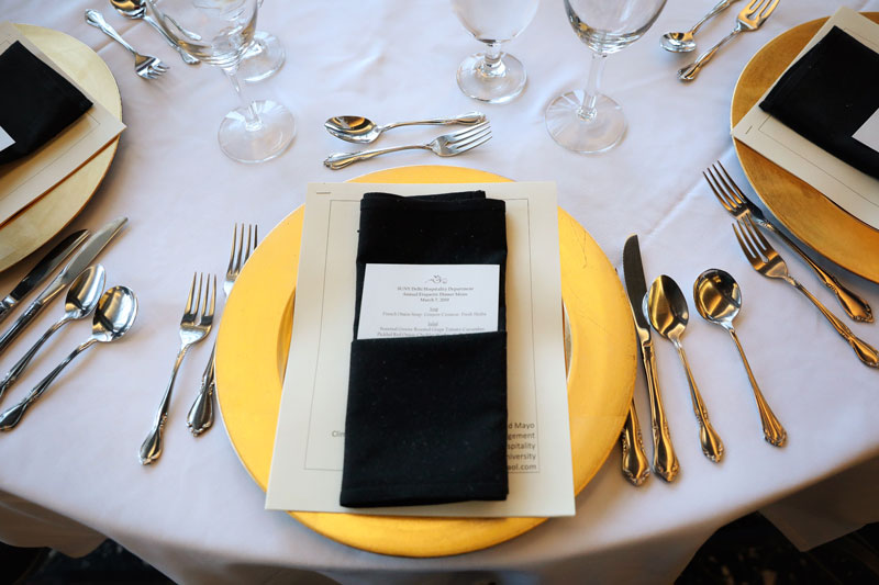 Formal place setting on dinner table with menu