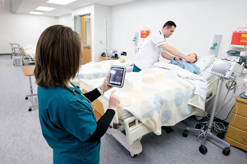 Nursing student practicing skills with mannequin on bed