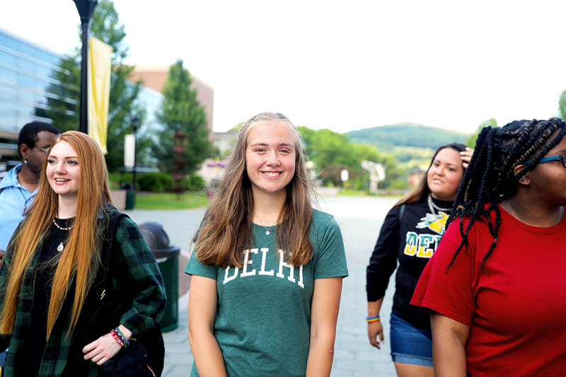 Four students walking on campus and smiling