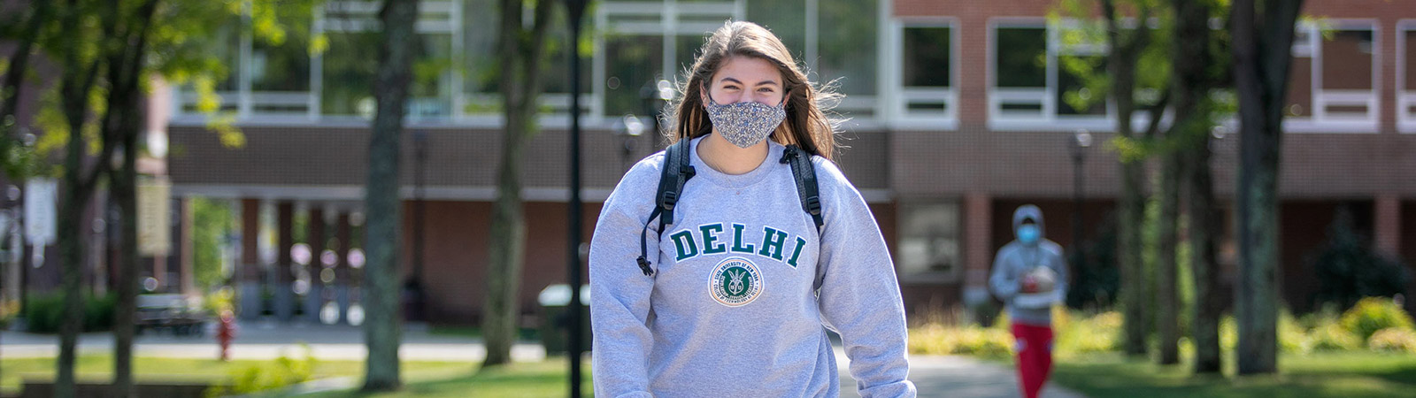 Student wearing a mask walking on campus.