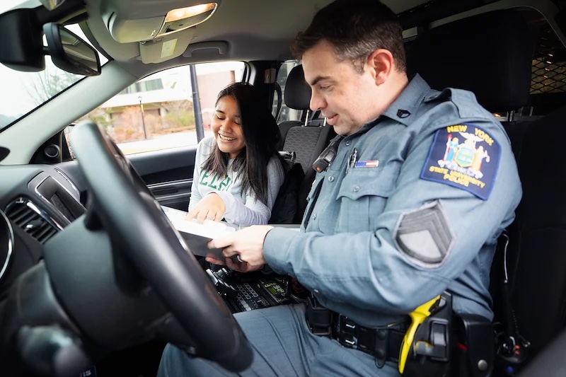 Officer with student in cop car