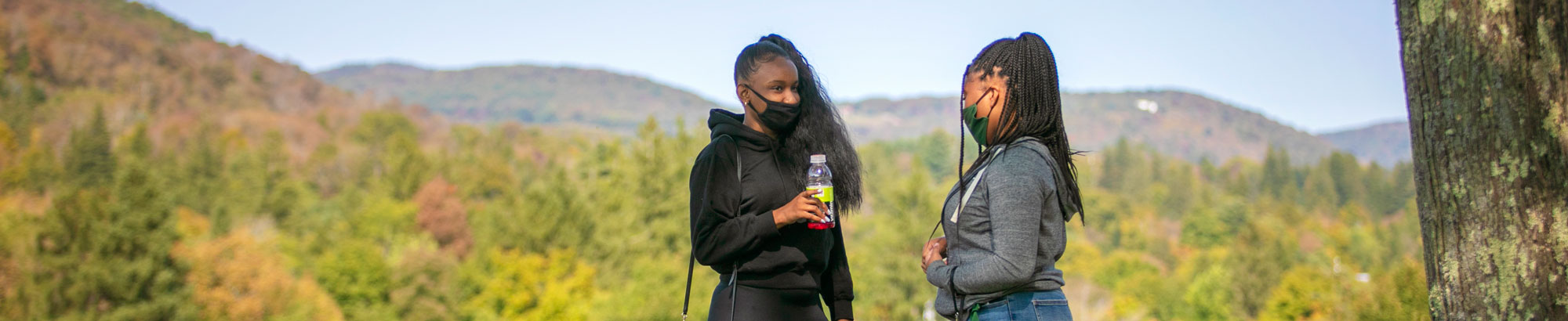 Two students standing with mountains in background