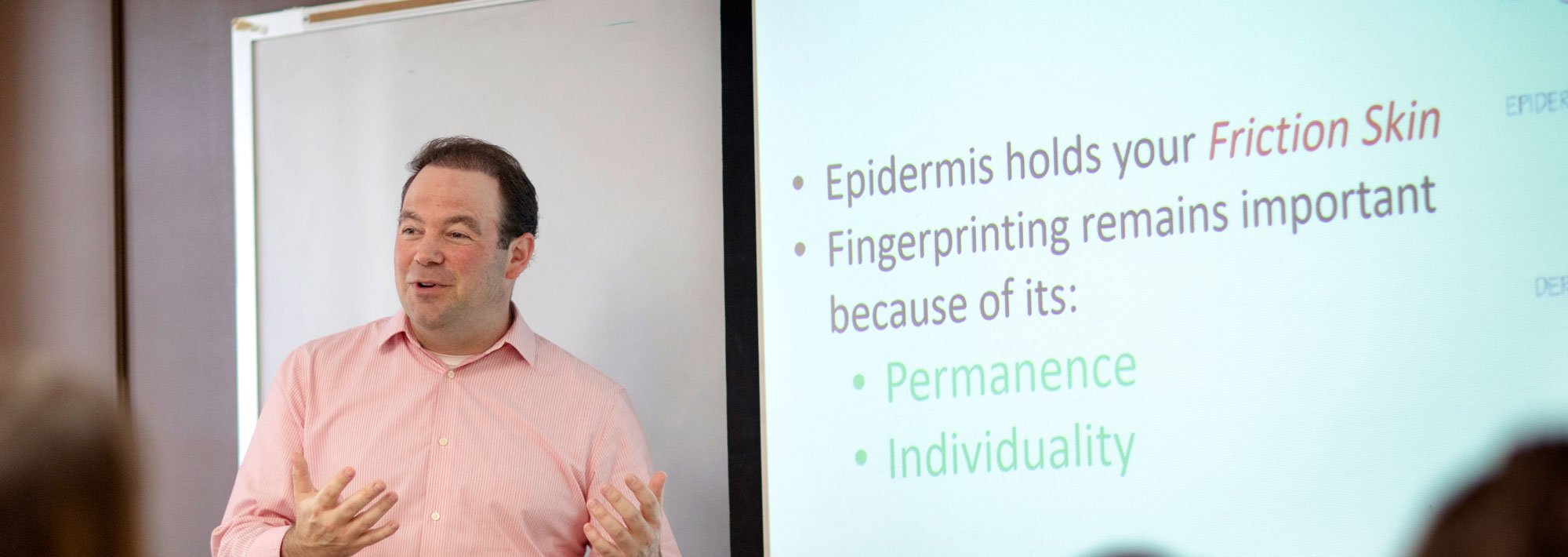 Teacher in salmon colored shirt giving a presentation