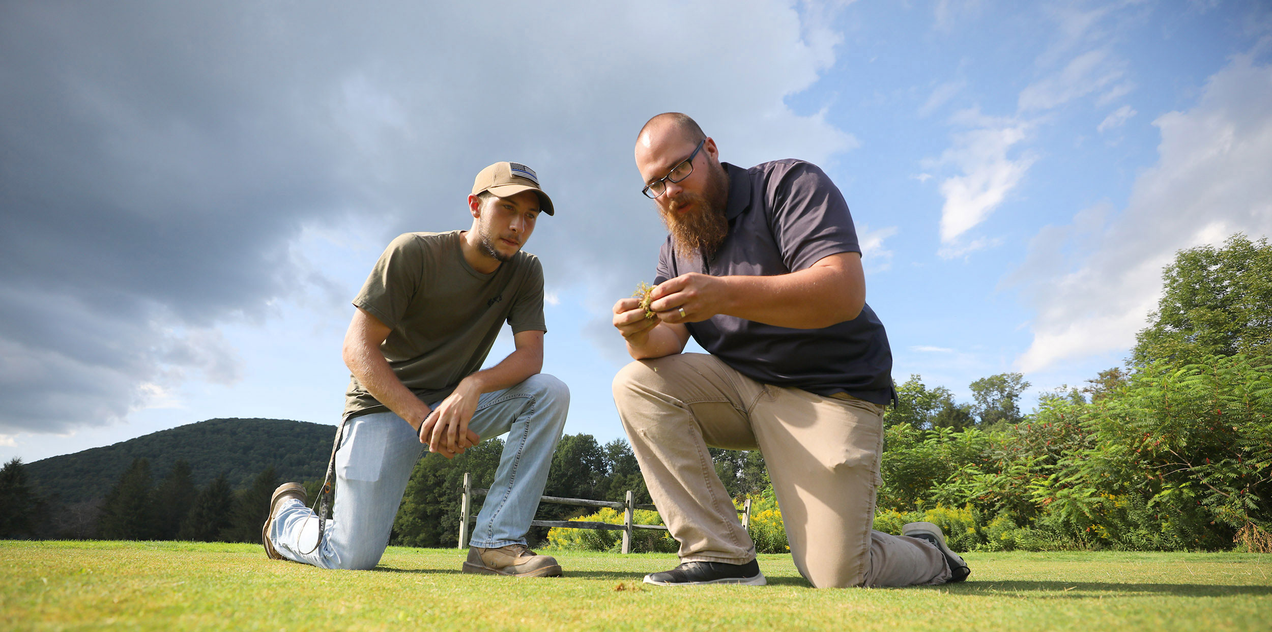 Teacher showing student some grass while kneeling